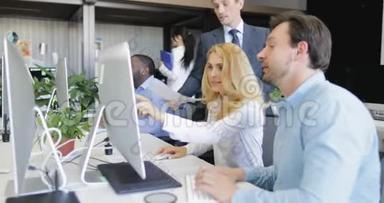 商务人士在现代创意办公室的电脑桌上讨论报告，商务人士团队会议